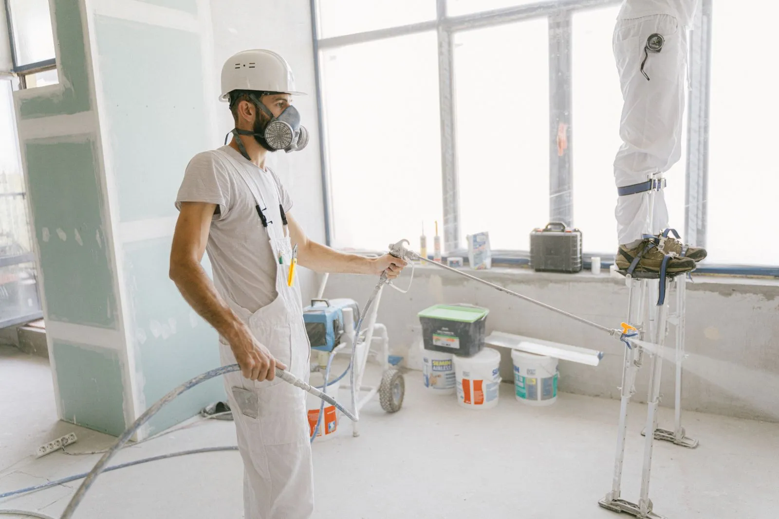 Maison en rénovation avec artisan posant une fenêtre et outils sur chantier lumineux